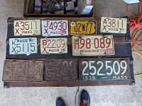Overview display of all 10 vintage motorcycle license plates arranged on a wooden surface for condition and variety assessment.