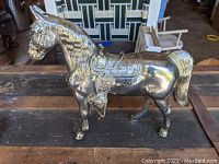 Side view of the chromed metal horse statue showing detailed saddle and overall shape