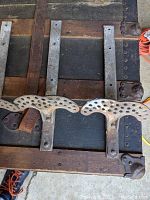 Photo showing several horse buggy steps laid out on a wooden surface, highlighting the perforated metal tread plate and mounting holes on the brackets.