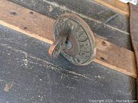 Side view of the antique Victorian copper doorbell turner mounted on wood, showing embossed text and lever handle.
