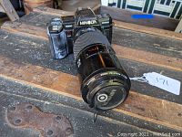 Minolta Maxxum 7000 camera with attached zoom lens angle view on wooden surface.