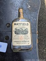 Front view of Mayfield bourbon bottle showing lithograph label with smokestack image and text.