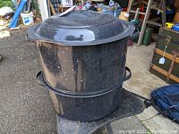 Full view of black enamelware clam steamer pot set including lid, pot, and insert.