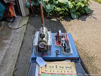 Engine and stack of magazines on driveway surface