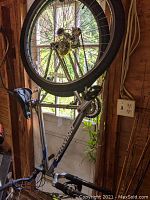 Side profile of Schwinn Ranger mountain bike hanging indoors, showing silver and blue frame, black saddle, pedals, tires, and suspension fork.
