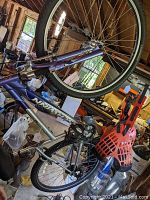 Blue and silver Schwinn mountain bike hanging indoors on a suspension hook, showing full side profile with tires, frame, and pedal visible.