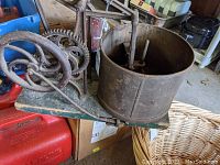 Side angle showing the large cast iron hand crank, multiple gears, wooden base, and large round drum of the chopper.
