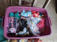 Pink bin filled with assorted Beanie Babies and some still inside plastic bags.