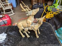 Front and side views of the brass statue showing the buck mounting the doe with detailed antlers and realistic animal features.