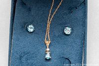 Pendand necklace and earrings displayed on blue velvet insert