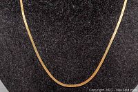 Gold chain laid flat on black background showing chain design