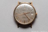 Front view of watch showing silvered dial, gold markers, hands and date window