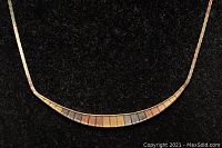 Close-up of curved bar section showing alternating yellow, rose and white gold rectangular tiles