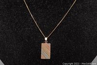 Close-up of rectangular pendant with diagonal tri-color stripes