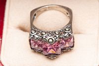 Close-up top view of the silver ring featuring three pink square-cut colored crystals and detailed silverwork.