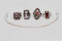 Photo showing the full set of the 925 silver tennis bracelet alongside the four rings with various colored stones.