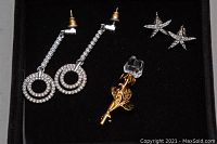 Close-up of Swarovski crystal earrings and crystal rose brooch displayed on black velvet.