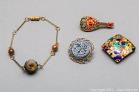 Murano glass bracelet with linked gold-tone chain and centerpiece bead, two micro-mosaic brooches including round floral and string instrument shaped, and square Murano glass pendant with colorful fleck pattern.