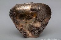 Front view showing embossed female profile and floral motifs