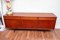 Front view of teak credenza showing three drawers on top and four sliding doors below