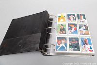 Black binder filled with baseball cards arranged in plastic sleeves, showing front sides of cards.