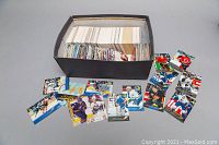 Shoebox filled with assorted hockey cards and MAD cards arranged loosely inside and some cards spread out for display.
