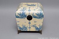 Front view of Victorian style decorative storage box showing blue toile fabric, metal clasp on front, and claw-foot metal legs.
