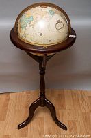 Full view of spinning globe on wooden tripod floor stand with circular wooden ring marked with increments for degrees.