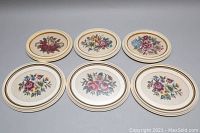 Six oval framed floral needlepoint wall art pieces arranged in two rows of three, showing overall set appearance and frame size differences.