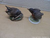 Two Boehm bird figurines on display surface.