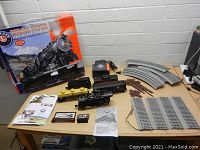 Display of the full train set including locomotive, tender, freight cars, tank car, controllers, and tracks with original box in background