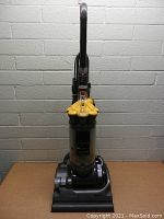 Front view of Dyson upright vacuum cleaner showing the clear dust canister and yellow filter parts.