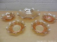 Five piece vintage carnival glass bowl set consisting of one large serving bowl and four smaller individual bowls with ruffled edges and iridescent finish.