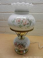 Full view of vintage 3-way lamp unlit showing floral painted white glass shade and base with chrome and brass metal components.