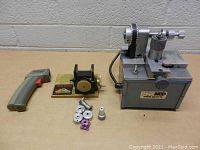 Image showing Max Mod tire turner, Pro Com Cobra tire truing tool, RC car control grip, and small metal parts arranged on a tabletop.