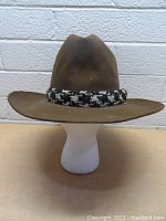 Front view of the brown felt Stetson hat showing wide brim and braided black and white hatband