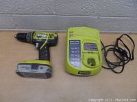 Ryobi 18 Volt cordless drill and charger placed side by side, showing drill with battery attached and charger with power cord coiled.