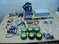 Full lot of RC car parts spread on a table showing motors, tires, wires, and hardware