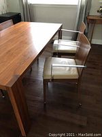 Side view of two chairs showing walnut-finish wooden frame, metal armrests, and beige pleather seats.