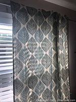 Curtain panel with grey and white leaf pattern hung on window
