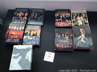 Image showing multiple Law & Order DVD box sets and a Game of Thrones box set on a black table.