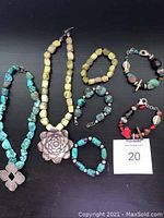 Full view of all necklaces and bracelets laid out on black background, showing variety of bead colors and silver pendants.