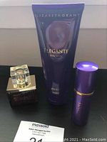 Three fragrance products: Elizabeth Grant Eau de Parfum, Elegante Body Lotion, Elegante Perfume Gel on black surface with MaxSold card.