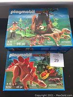 Front view of Playmobil 5233 and 5232 dinosaur sets in original boxes showing artwork and piece count