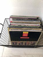 Black wire basket filled with stacked vinyl records, front view