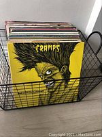 Black metal wire basket filled with vinyl records featuring The Cramps album 'Bad Music for Bad People' visible in front