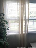 Curtain panels hanging on window showing translucent ivory linen fabric and length.