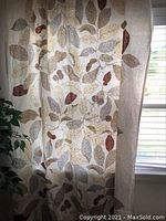 Curtain panel hung on window showing leaf pattern and natural colors