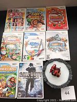 Photo showing 8 Nintendo Wii game cases with one Skylanders figure on a circular base for scale and content verification.