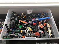 Plastic container filled with assorted assembled Lego vehicles and pieces